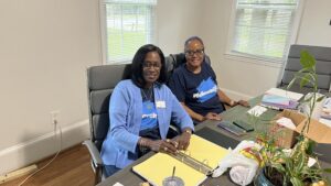 two member of the SAU NAA sitting at a table, looking at the camera in support of SAU