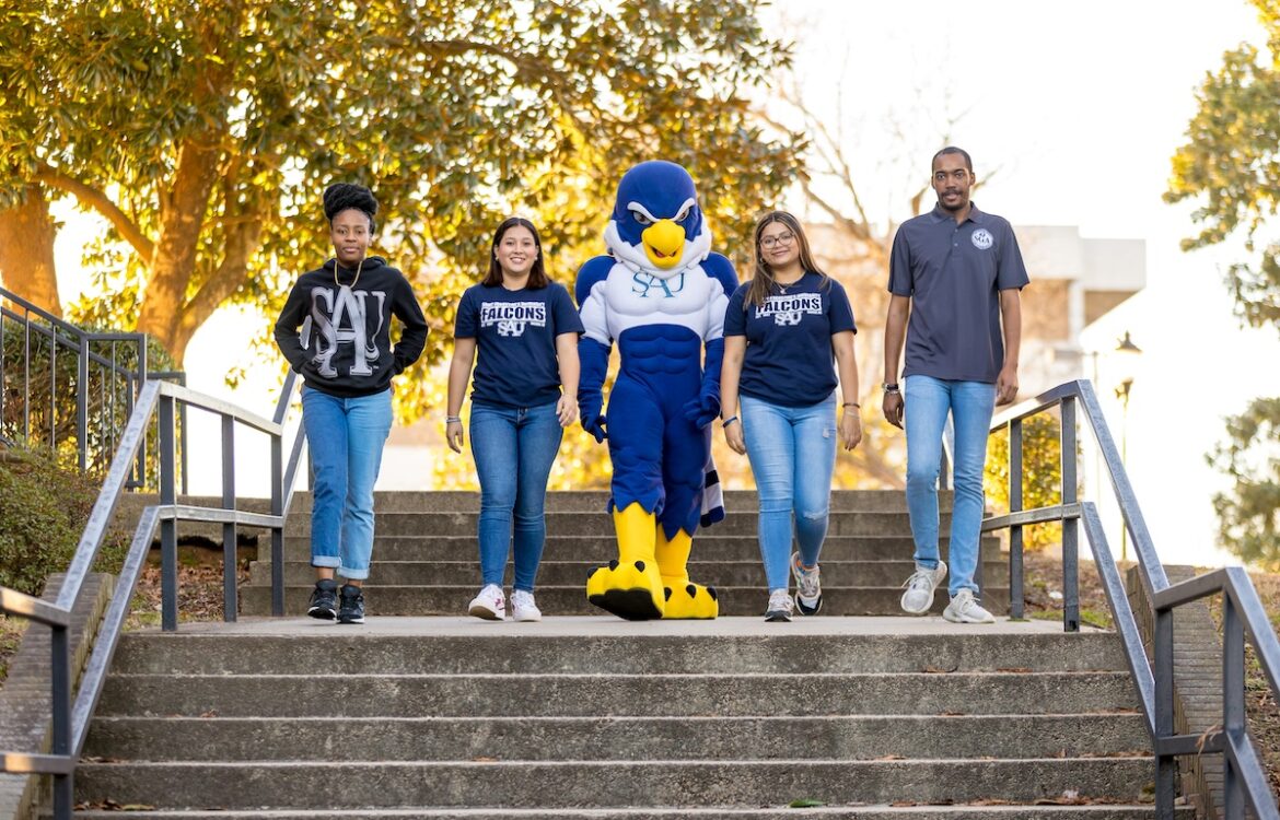 Four students walking down the outdoor steps with Auggie the mascot