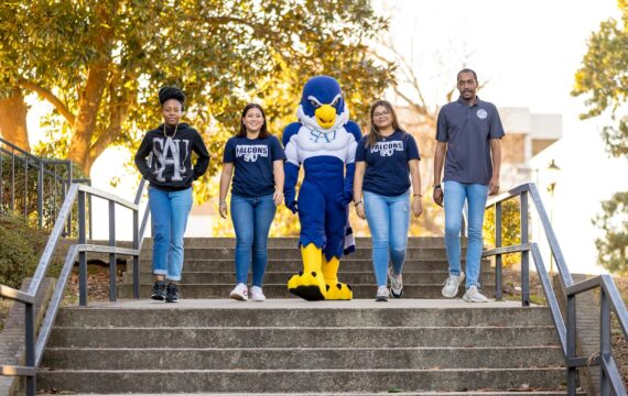 Four students walking down the outdoor steps with Auggie the mascot